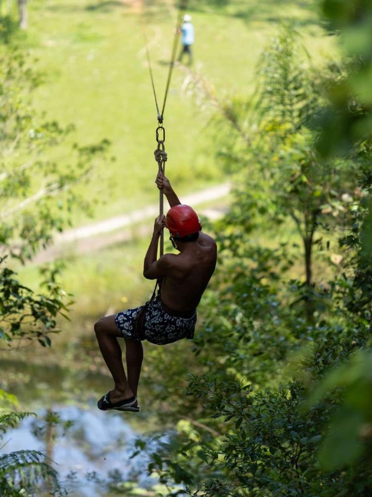 Participante descendo de tirolesa sobre o lago
